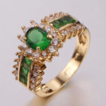 um anel grande de ouro com pedras verdes