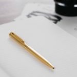 uma caneta de ouro em uma folha de papel